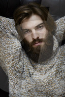 Young Man wearing a wool Pullover and sitting on an Armchair