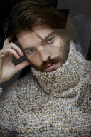 Young Man wearing a wool Pullover and sitting on an Armchair