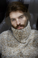 Young Man wearing a wool Pullover and sitting on an Armchair