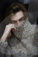 Young Man wearing a wool Pullover and sitting on an Armchair