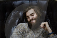 Young Man wearing a wool Pullover and sitting on an Armchair