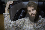 Young Man wearing a wool Pullover and sitting on an Armchair