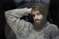 Young Man wearing a wool Pullover and sitting on an Armchair