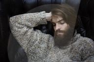 Young Man wearing a wool Pullover and sitting on an Armchair