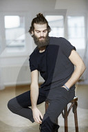 Young Man wearing a black T-Shirt and sitting on a Stool