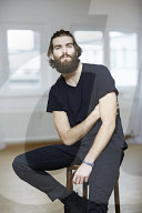 Young Man wearing a black T-Shirt and sitting on a Stool