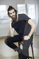 Young Man wearing a black T-Shirt and sitting on a Stool
