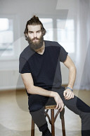 Young Man wearing a black T-Shirt and sitting on a Stool