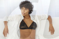 Young Woman in Lingerie sitting on a white Couch 