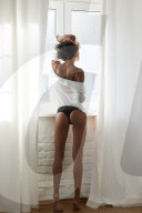 Young Woman wearing Lingerie standing at a Window