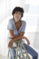 Young woman wearing a T-Shirt and sitting on a wooden Ladder