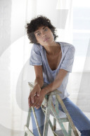 Young woman wearing a T-Shirt and sitting on a wooden Ladder