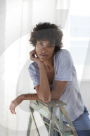 Young woman wearing a T-Shirt and sitting on a wooden Ladder