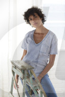 Young woman wearing a T-Shirt and sitting on a wooden Ladder
