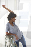 Young woman wearing a T-Shirt and sitting on a wooden Ladder