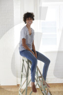 Young woman wearing a T-Shirt and sitting on a wooden Ladder