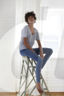 Young woman wearing a T-Shirt and sitting on a wooden Ladder