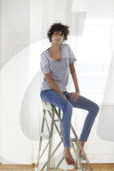 Young woman wearing a T-Shirt and sitting on a wooden Ladder