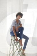Young woman wearing a T-Shirt and sitting on a wooden Ladder