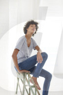 Young woman wearing a T-Shirt and sitting on a wooden Ladder