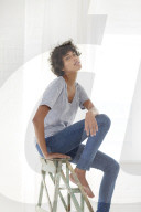 Young woman wearing a T-Shirt and sitting on a wooden Ladder
