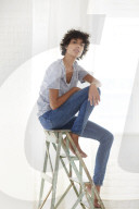 Young woman wearing a T-Shirt and sitting on a wooden Ladder