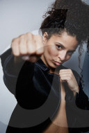 Woman with curly Hair wearing a Blazer is shadow boxing