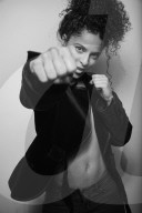 Woman with curly Hair wearing a Blazer is shadow boxing