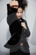 Woman with curly Hair wearing a Blazer is shadow boxing