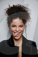 Woman with curly Hair wearing a Blazer sticking Tongue out