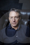 Mature Man sitting on a Leather Wing Chair