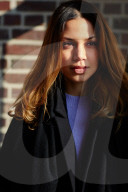  Woman wearing a black Coat and standing in front of a Brick Wall