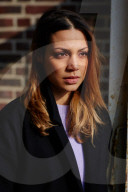  Woman wearing a black Coat and standing in front of a Brick Wall