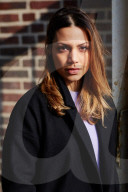  Woman wearing a black Coat and standing in front of a Brick Wall