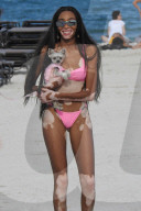 Supermodel Winnie Harlow is seen in an adorable picture as she posed with a super cute little dog
dressed in pink doggie clothing that matched her pink bikini. 
