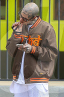 Rapper Rick Hilfiger appears to smoke a suspicious cigarette as he relaxes on the streets of LA despite the coronavirus shutdown