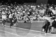 Lee Evans , of the United States , looks back as he crosses the finish line of the Olympic 4x400 metres relay race as America wins another gold medal in the new world and Olympic record time of 2 minutes 56.1 seconds . Following are Daniel Rudisha ( 571 )
