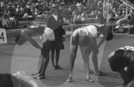 An attractive girl track official watches athletes gasping for breath after the Olympic 400 metres final . The winner , Lee Evans of the USA is on the right , silver medallist Larry James , left , and Poland's Andrzej Badenski , centre , was seventh .

