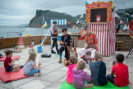 'Telly just isn't the same': glorious return of English seaside entertainment. People young and old enjoy silly fun of Uncle Tacko’s flea circus and a Punch and Judy show in Devon