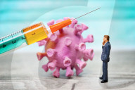 NEWS - Coronavirus: Figur vor Coronavirus mit Impfspritze