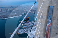 FEATURE -  Arbeiter reinigen Eis von einer 300m hohen Brücke in Wladiwostock