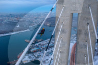 FEATURE -  Arbeiter reinigen Eis von einer 300m hohen Brücke in Wladiwostock