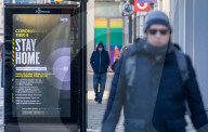 Members of the public walk past a Covid-19 information display as Ministers reveal that the Oxford vaccine could be approved next week.