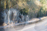 FEATURE - Das gefrorene Wasser aus einer Pfütze verursacht eine bizarre Eisformation am Strassenrand im britischen Headley