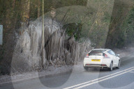 FEATURE - Das gefrorene Wasser aus einer Pfütze verursacht eine bizarre Eisformation am Strassenrand im britischen Headley