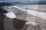 Icebergs at sunrise on Jokulsarlon Beach, a black volcanic sand beach in South East Iceland