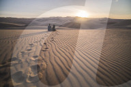 Couple watching the sunset over sand dunes in the desert at Huacachina, Ica Region, Peru