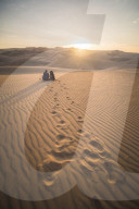 Couple watching the sunset over sand dunes in the desert at Huacachina, Ica Region, Peru