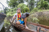 Young boy in dugout canoe with speared piranha on the San Miguel CaÃ±o, Loreto, Peru