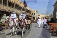 Busy street scene with traditionally dressed mounted policemen and shoppers, Souq Waqif, Doha, Qatar, Middle East